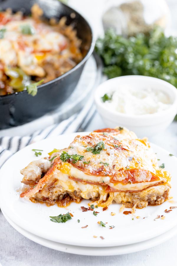 a slice of crustless pizza on a white dinner plate with a castiron skillet casserole sits in the background