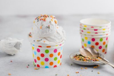 a multi-colored polka dotted cup with vanilla ice cream topped with colorful sprinkles