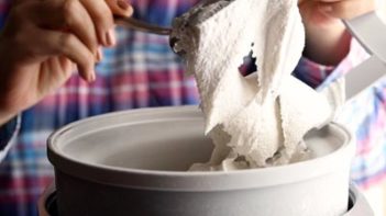 lifting the churn from an ice cream maker showing the creamy vanilla ice cream