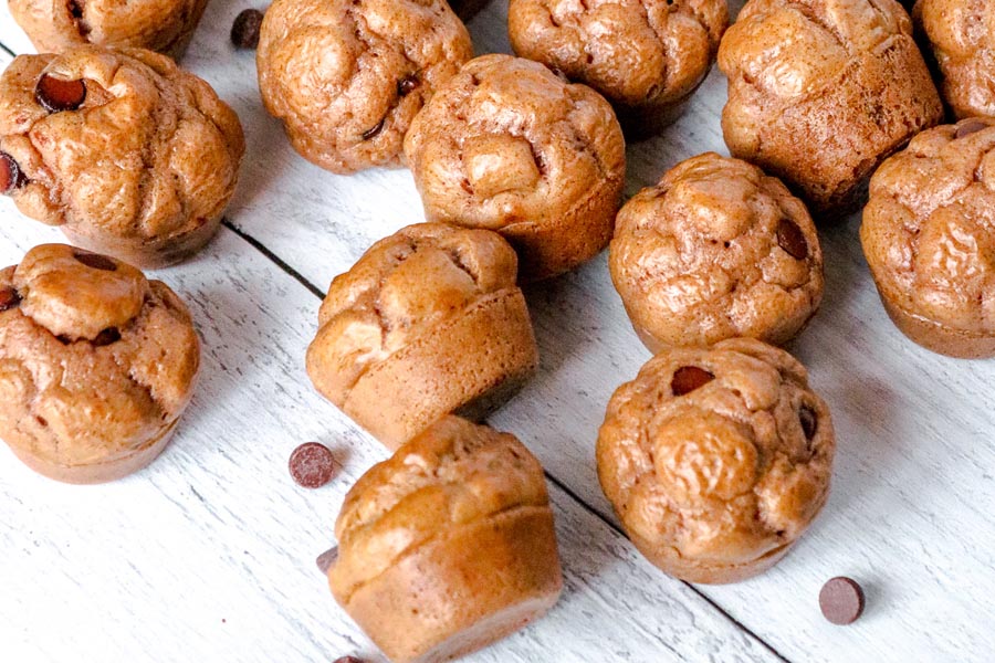 a bunch of keto muffins on a white board with chocolate chips scattered around