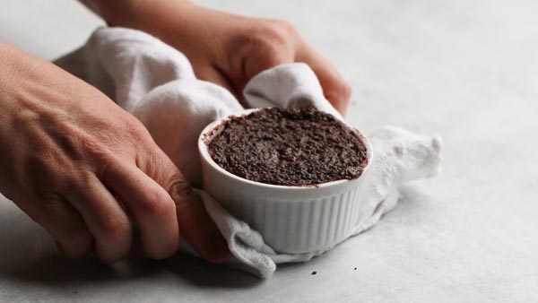 pulling a keto mug cake out of the oven with a white towel