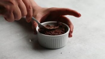 pressing chocolate cake batter into a small white ramekin