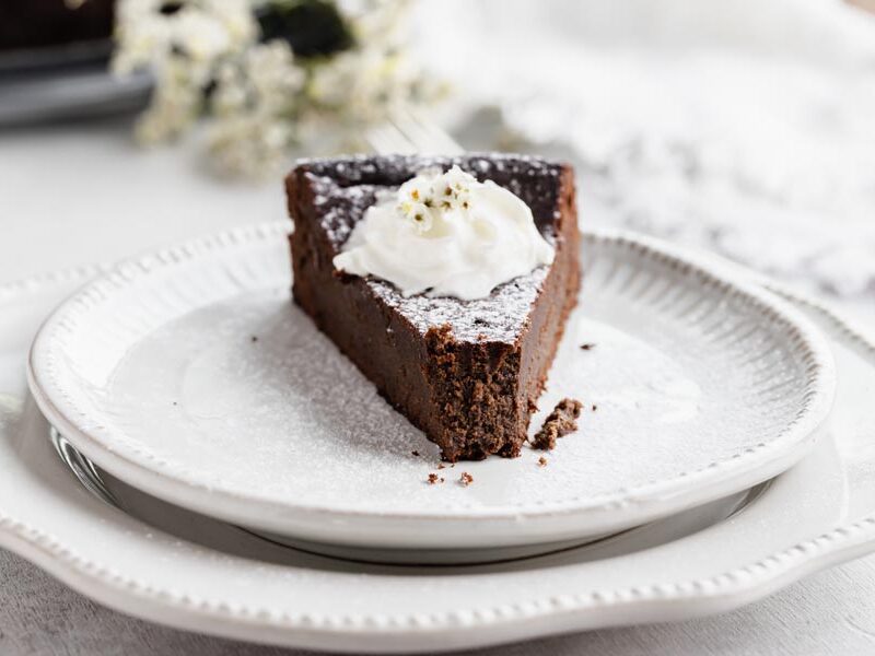 a slice of cake on a plate topped with whipped cream and a bite taken out of the top