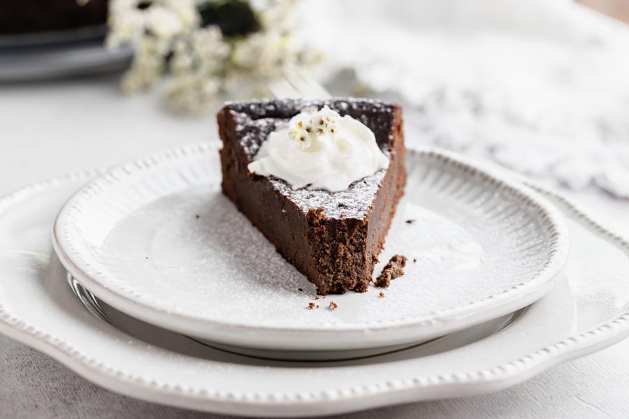 a slice of cake on a plate topped with whipped cream and a bite taken out of the top