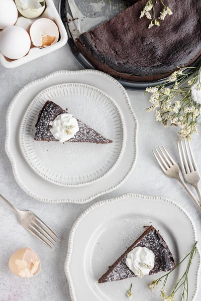 two slices of cake on plates next to the whole cake and a bunch of eggs