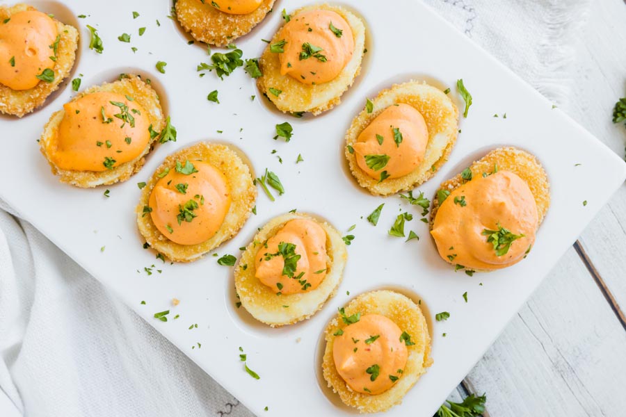 fried deviled eggs in an egg tray topped with parsley