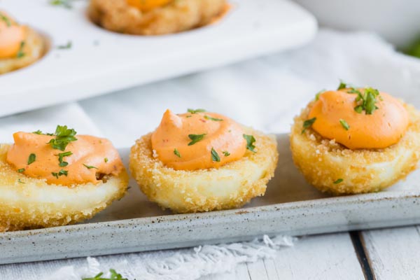 three fried deviled eggs with a creamy orange filling