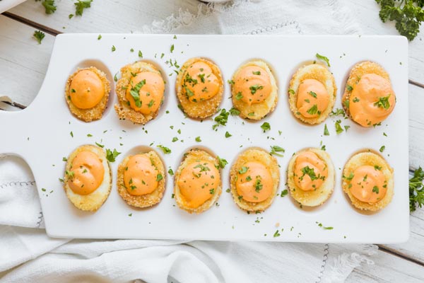 a platter with deviled eggs on it sprinkled with parsley