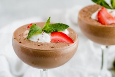 two elegant looking frozen hot cocoa topped with berries and whipped cream