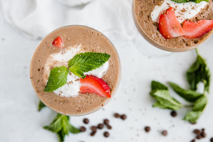 top down view of a couple glasses of a frozen chocolate drink with berries and cream