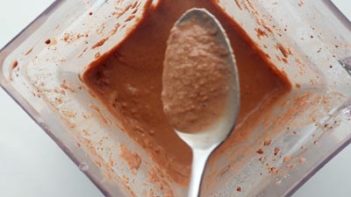 scooping chocolate frosty with a spoon from a blender