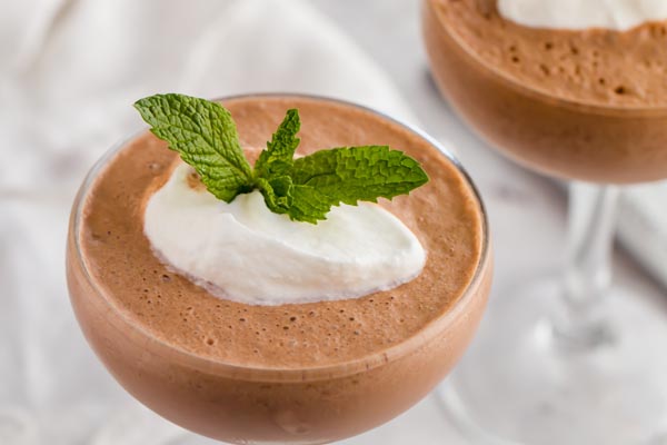 two frozen hot chocolate drinks with a dollop of whipped cream and a sprig of mint