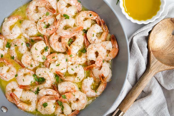 buttery shrimp in a skillet next to extra butter and spoon