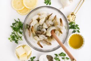 mixing raw shrimp with a wooden spoon in a bowl