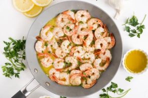a skillet with cooked shrimp with parsley on top