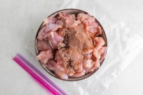 Seasoning dusted on top of cubed chicken in a big bowl.