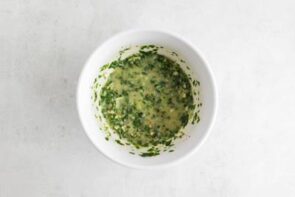 A small bowl with butter, parmesan, garlic and parsley sauce.
