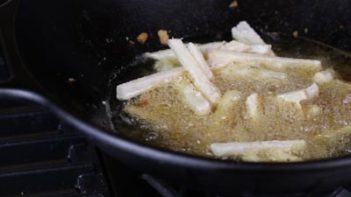 frying keto jicama fries in a skillet with avocado oil