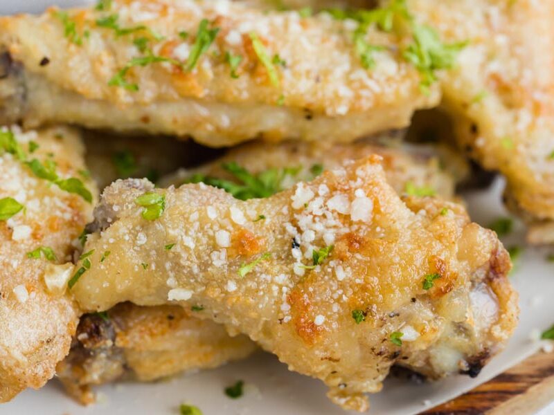 Close up of a crispy drumette wing topped with freshly grated parmesan and parsley.