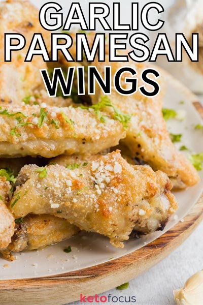 Crispy party wings on a white plate next to a clove of garlic.