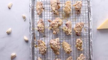 Wings coated with garlic parmesan butter on a baking tray.