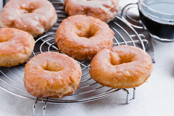 glazed keto donuts on a circular wire rack with a cup of black coffee
