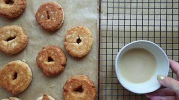 keto donuts cooling on some parchment paper with a wire rack nearby