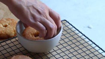 dipping a donut into glaze