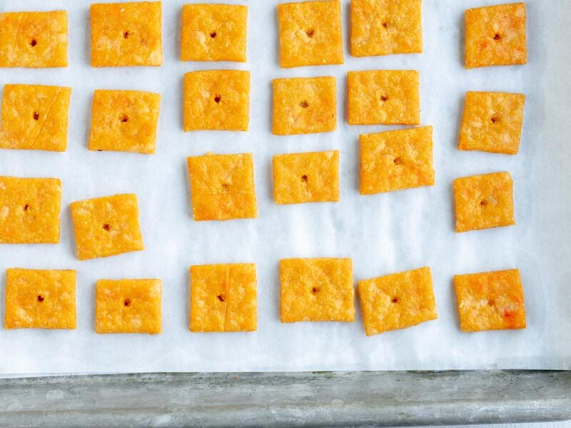 A baking tray with baked cheese crackers in a row.