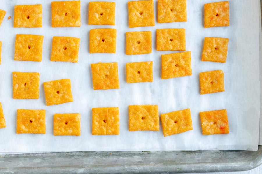 A baking tray with baked cheese crackers in a row.