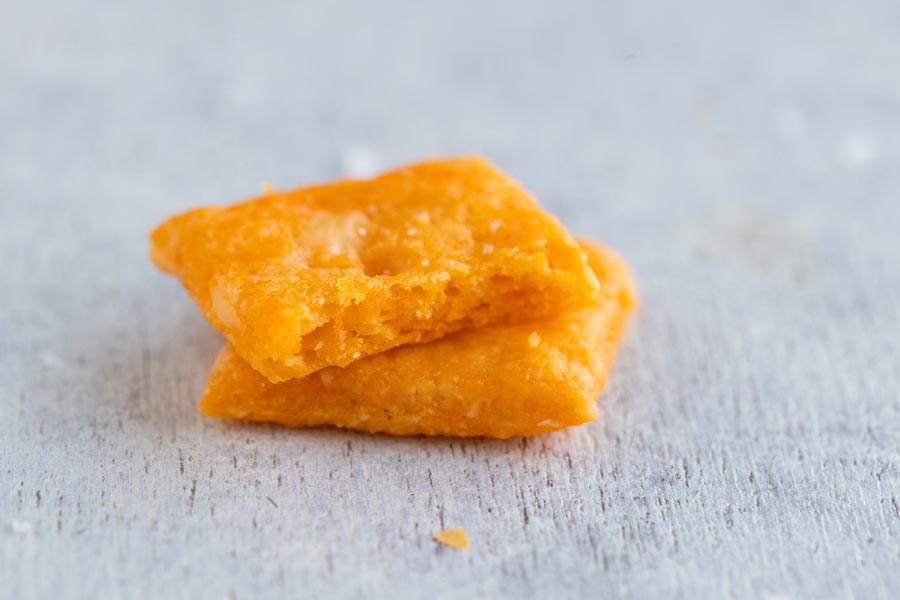 Two crackers stacked on each other. The top cracker is bitten in half to show the crunchy inside.