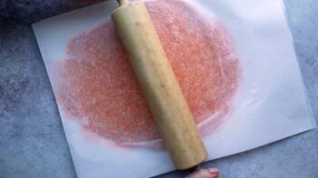 Rolling out orange cracker dough with a rolling pin.