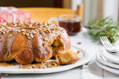 pull-apart monkey bread on a serving plate next to plates and forks with coffee and presents in the background