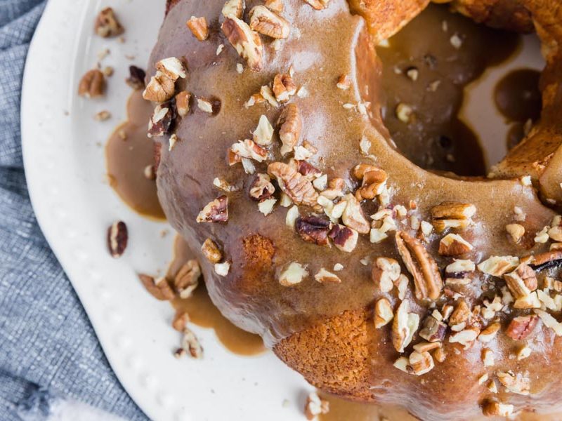 caramel syrup covering a bundt bread with crushed pecans on it