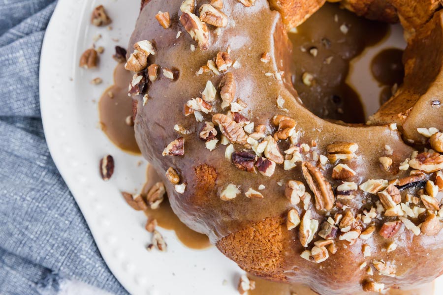 caramel syrup covering a bundt bread with crushed pecans on it