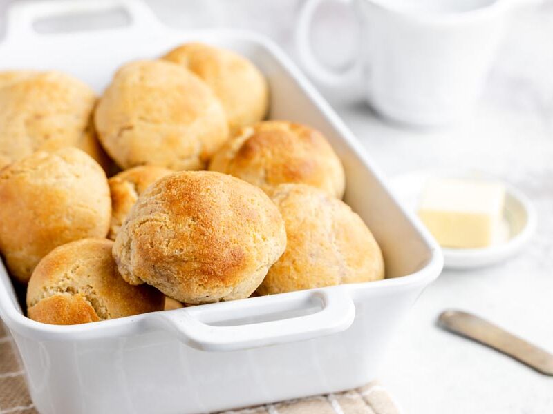 A white casserole dish filled with keto-friendly yeast rolls, served alongside a pat of butter and coffee.