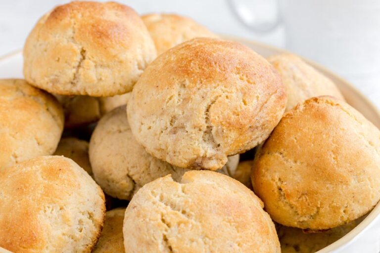 A close-up of soft, golden yeast rolls highlighting the cracked tops and fluffy texture.
