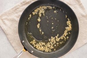 a skillet with oil and minced garlic cooking