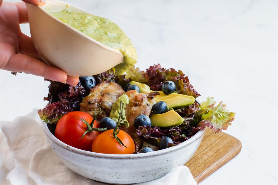 pouring green goddess dressing on a salad