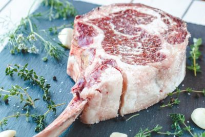 a raw tomahawk steak right after seasoning from salt