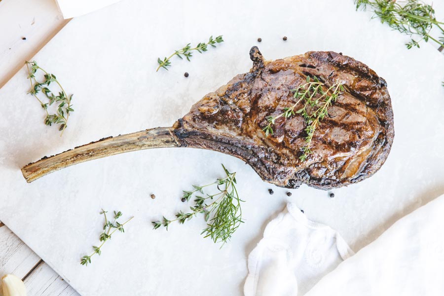 grilled prime cut tomahawk steak with thyme on top
