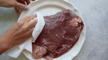 Patting steak dry with a paper towel.