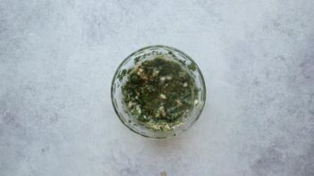A small glass dish with herb marinade inside.