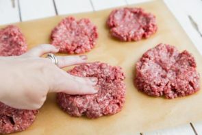 six beef patties on a sheet of parchment paper