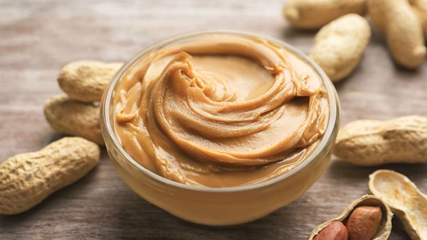 creamy peanut butter in a small bowl with peanuts
