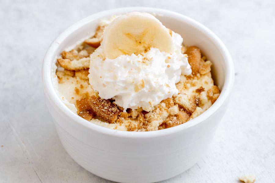 Crushed wafers and whipped cream top a bowl of banana pudding.