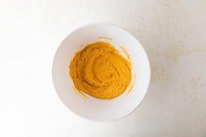 Thick pumpkin cookie dough is shown in a white bowl after dry ingredients are incorporated.