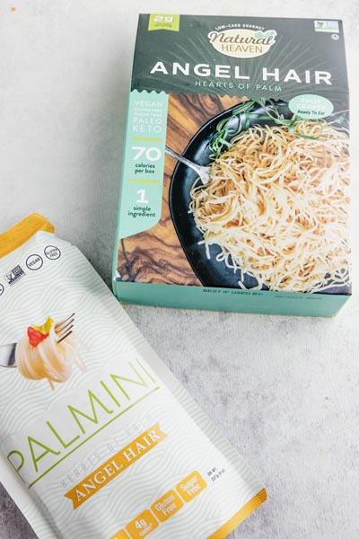 a box of angel hair hearts of palm pasta by Natural Heaven sits above a bag of Palmini noodles