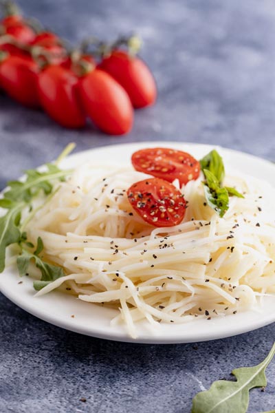 a plate of palm noodles topped with lettuce and tomato slices