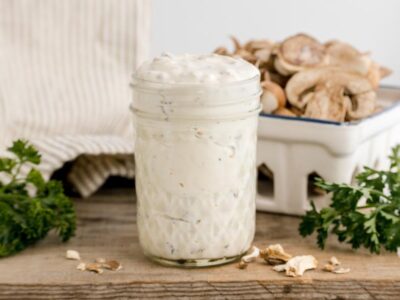 Homemade keto cream of mushroom soup served in a glass jar with fresh mushrooms and parsley in the background.